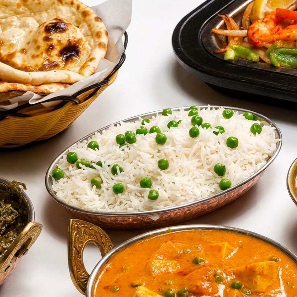 A spread of Indian dishes including naan, pea rice, shrimp, saag, paneer, and dal.